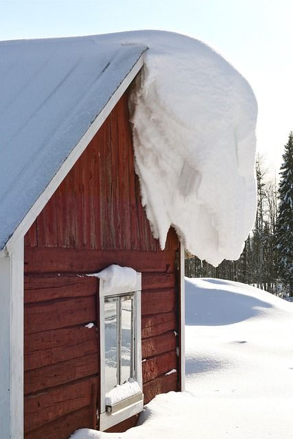 Large snow drift on the edge of a farmhouse roof in Anchorage Alaska. 