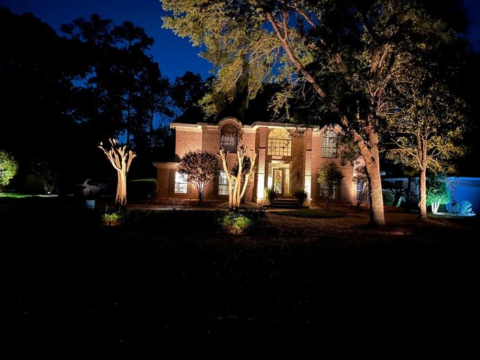 a large brick house is lit up at night surrounded by trees .