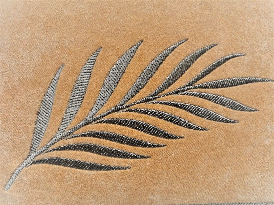 Foglia di palma grigia ricamata su sfondo beige.