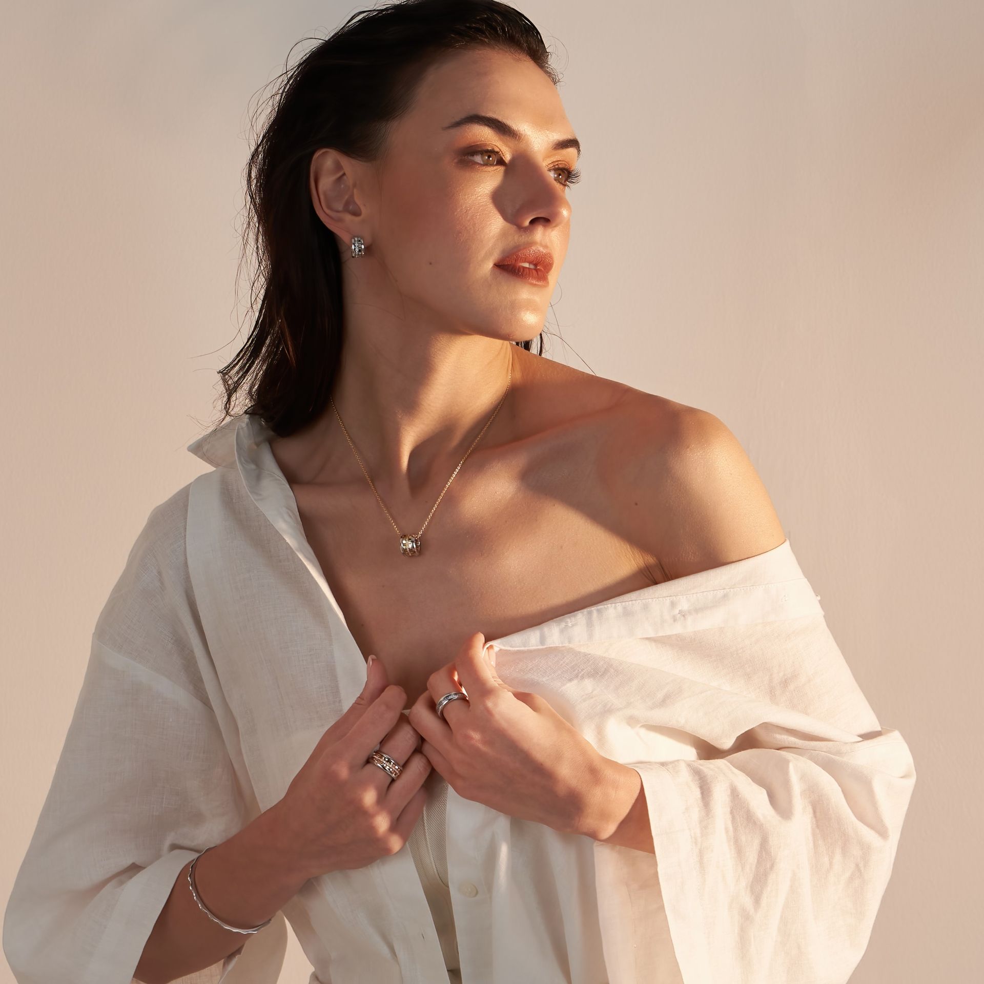 Eine Frau trägt ein weißes Hemd und hochwertigen Goldschmuck