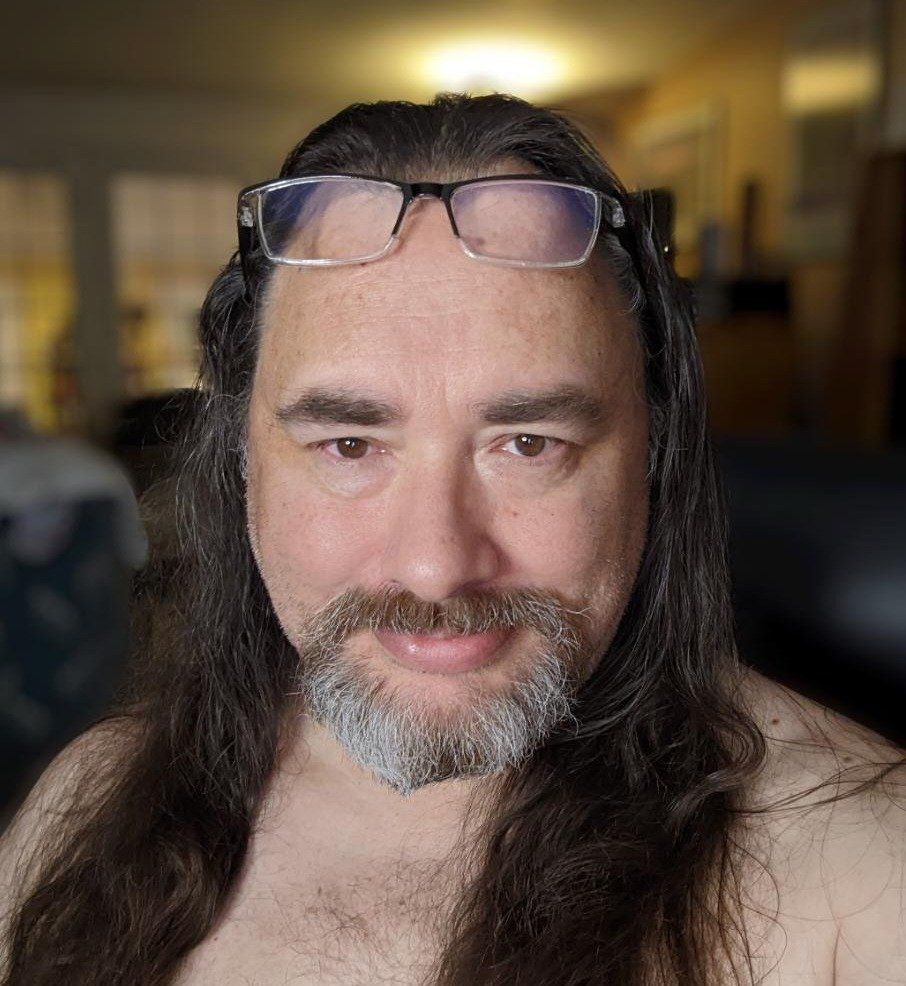 Darrell Delph, long hair and a beard wearing glasses.