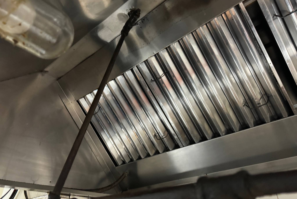 Inside of a stainless steel commercial kitchen exhaust hood.