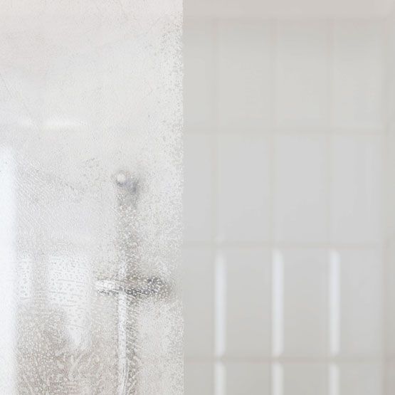 a close up of a glass shower door that has hard water spots