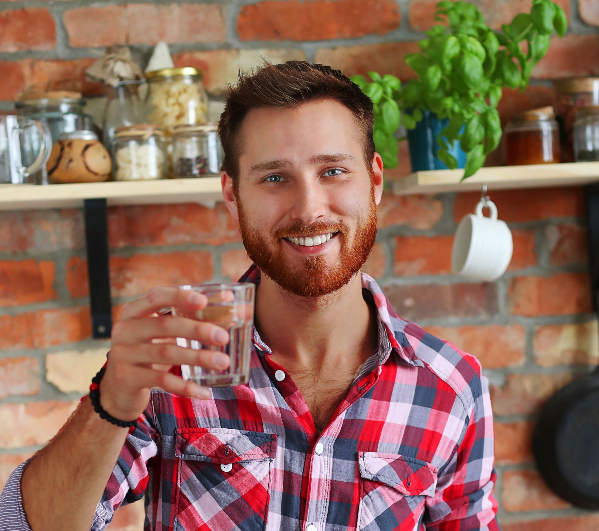 A man in a plaid shirt is holding a glass of water in his hand. Clean up your water with SoCal Water Solutions