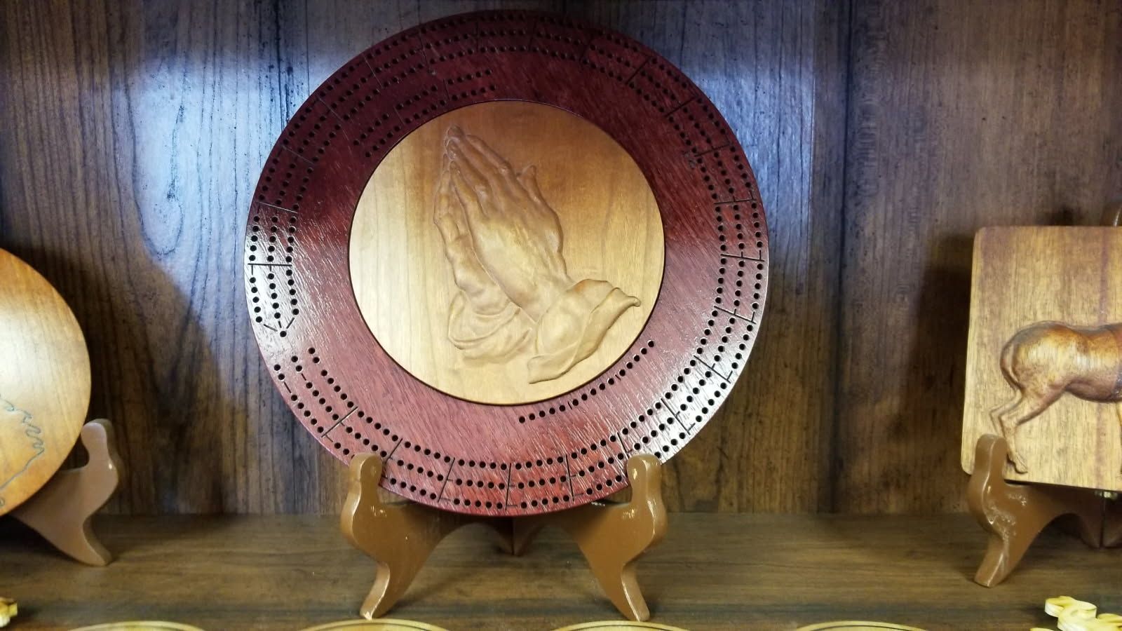A wooden plate with a praying hand on it