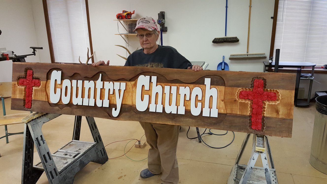 A man is holding a wooden sign that says country church.