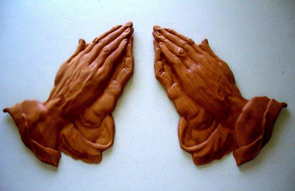 A pair of brown praying hands on a white surface