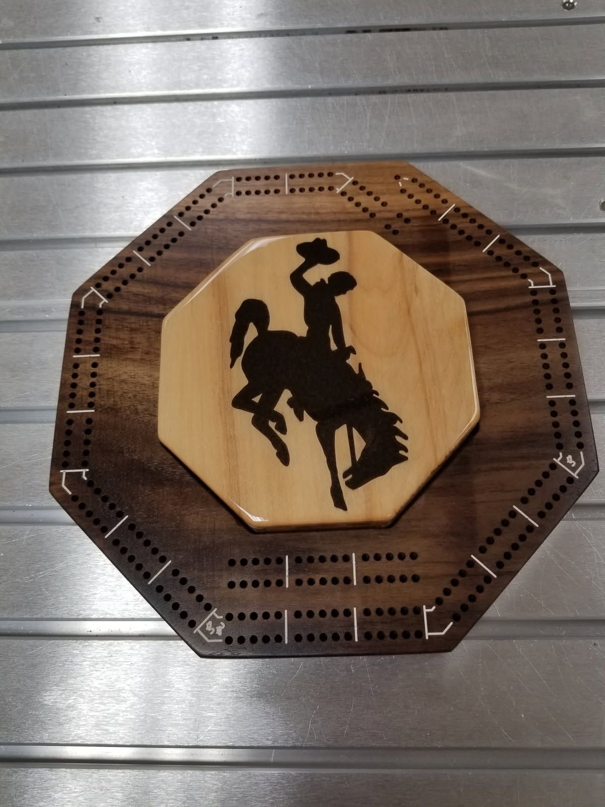A wooden cribbage board with a cowboy on a bucking horse