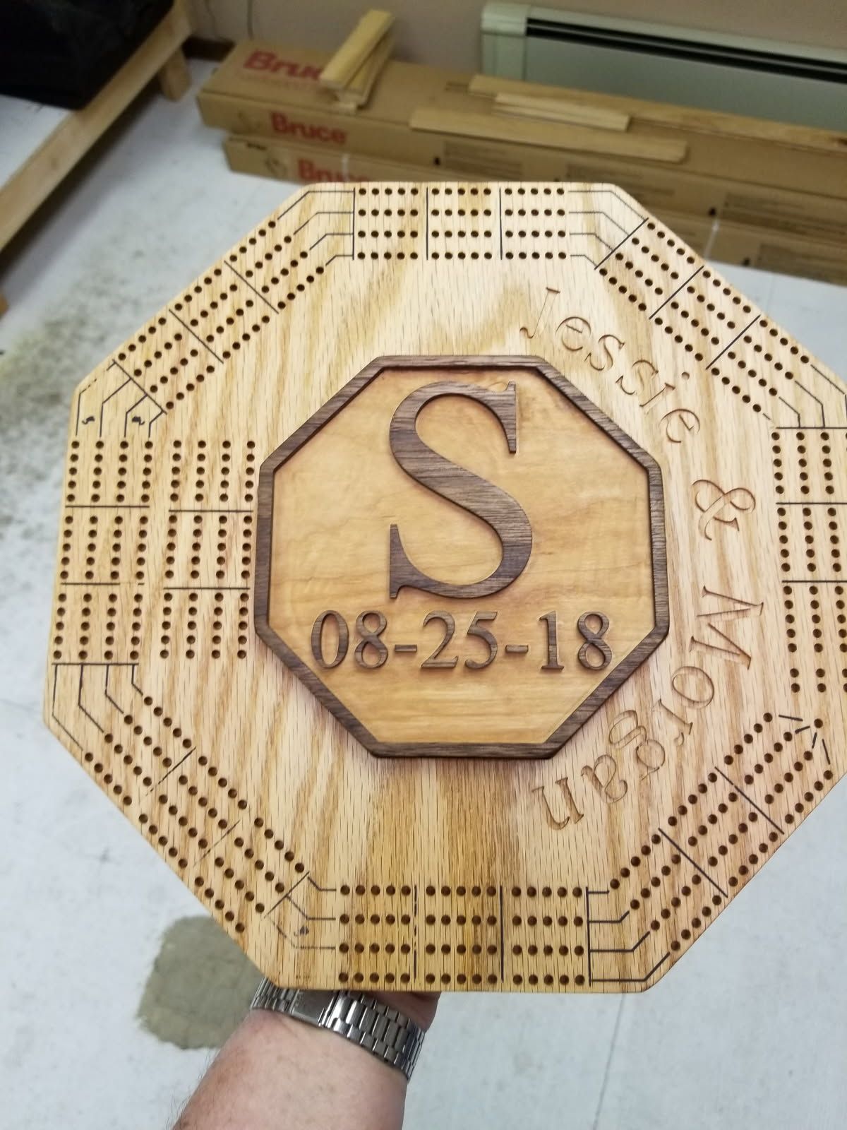 A person is holding a wooden cribbage board with the date 08-25-18 on it