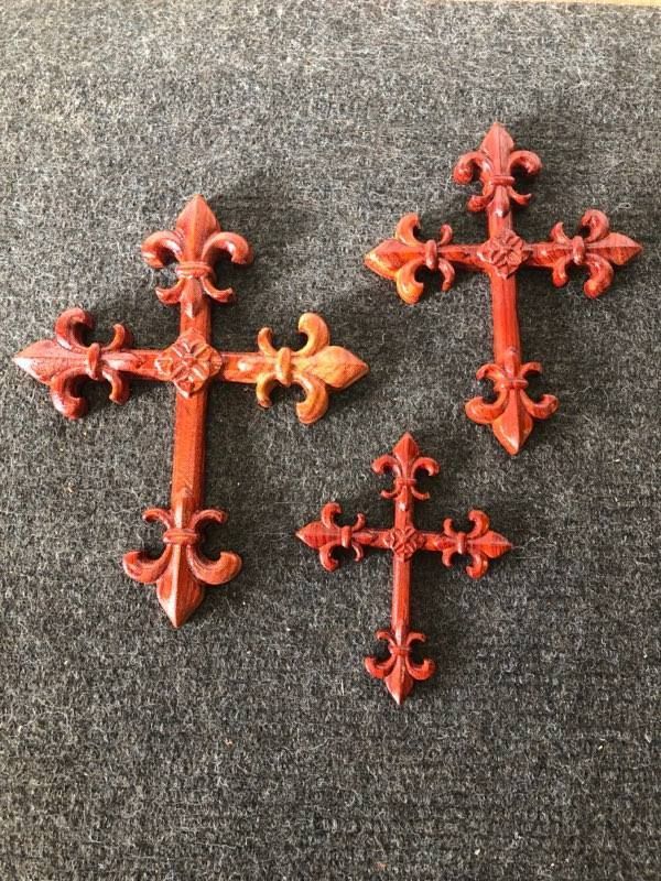 Three red crosses are sitting on a gray surface.