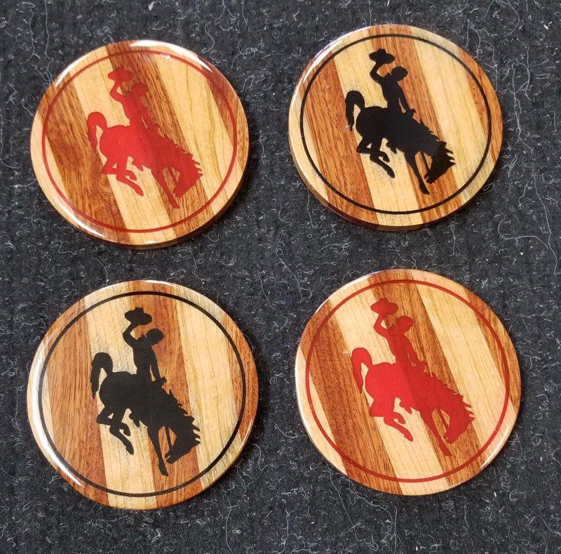 Four wooden coasters with a cowboy on a bucking horse on them