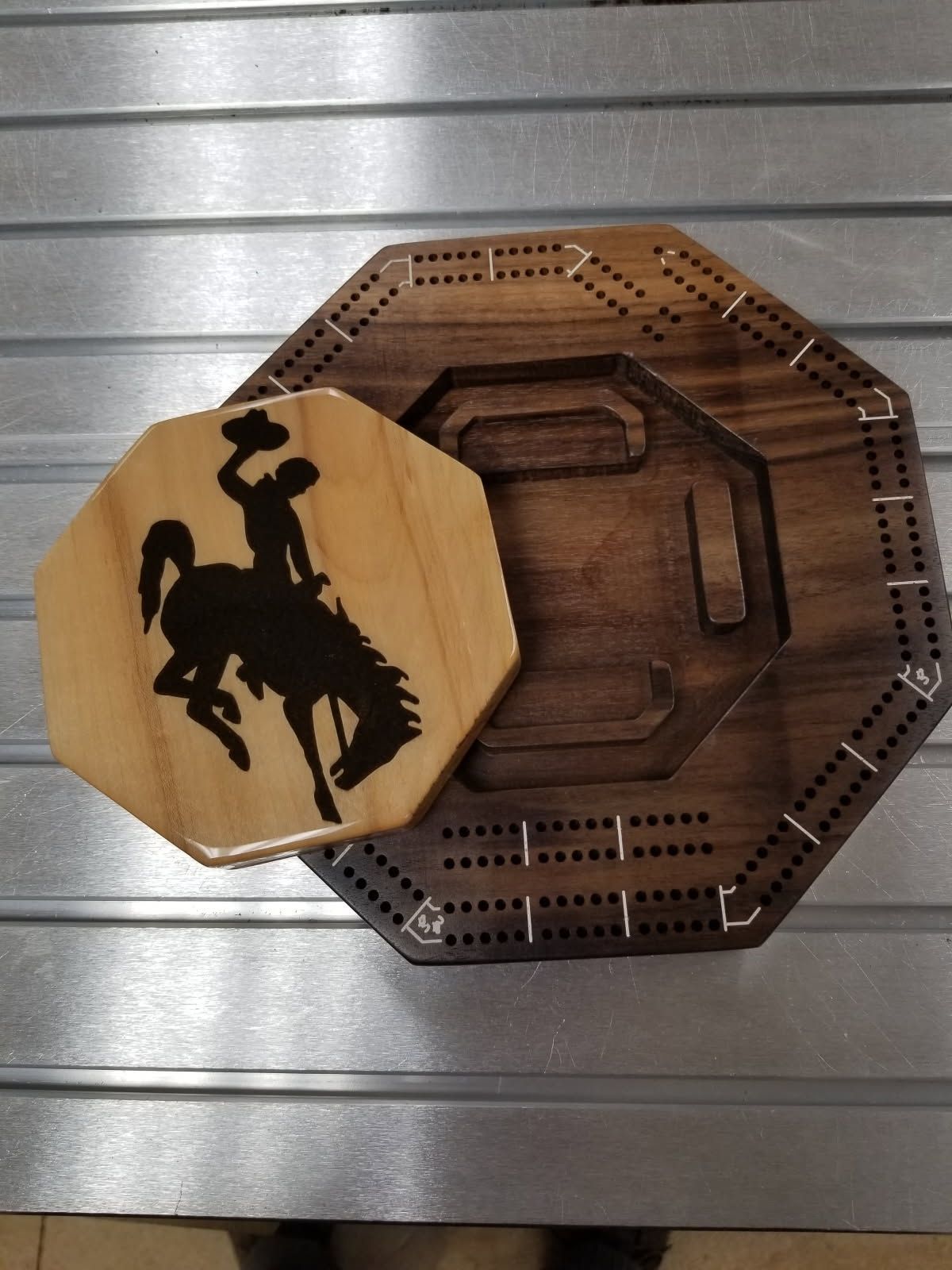 A wooden cribbage board with a bucking bronco on it