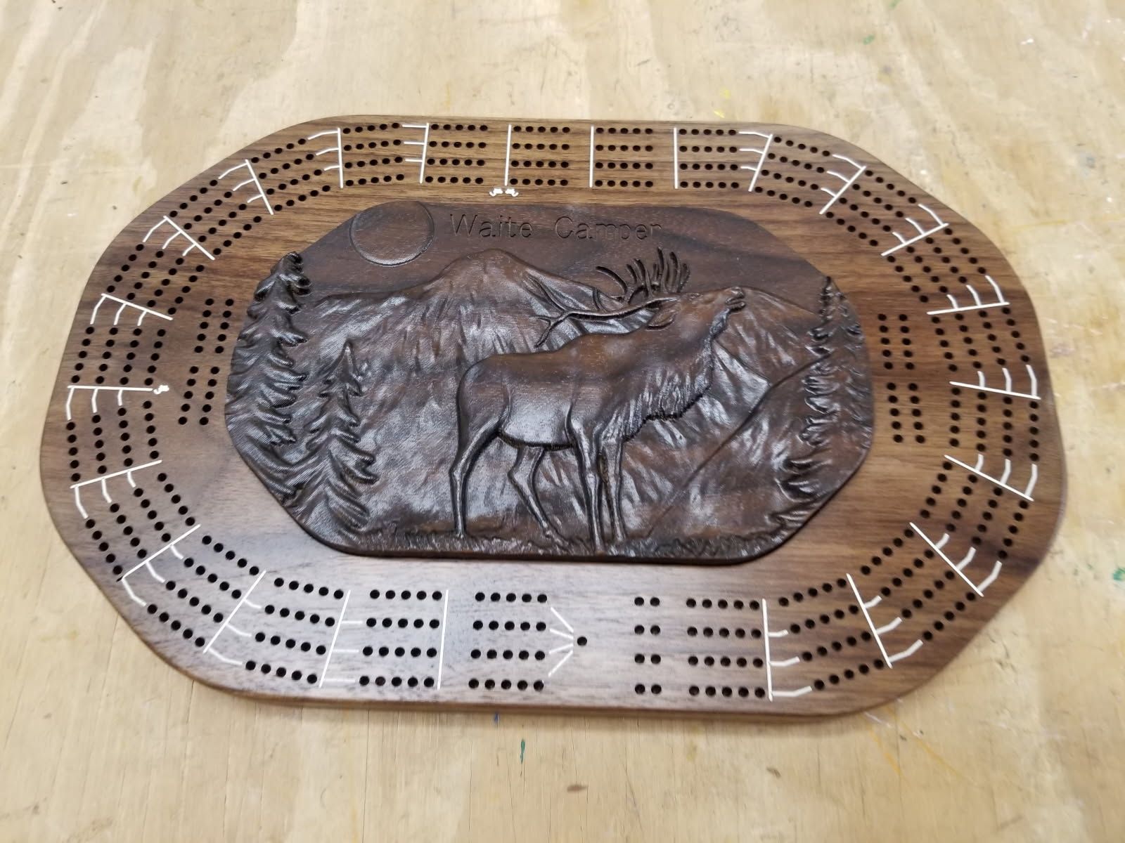 A wooden cribbage board with a picture of a moose on it