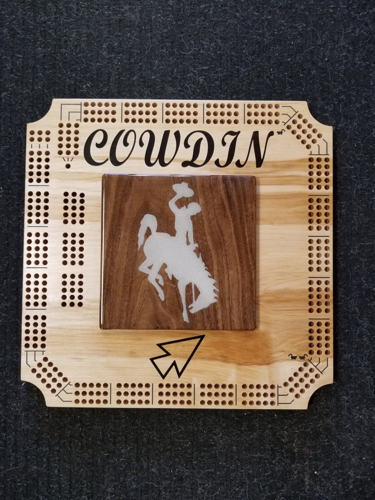 A wooden cribbage board with the name cowdin on it