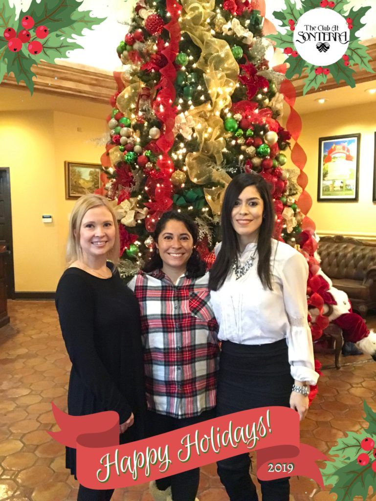Three women are posing for a picture in front of a christmas tree.