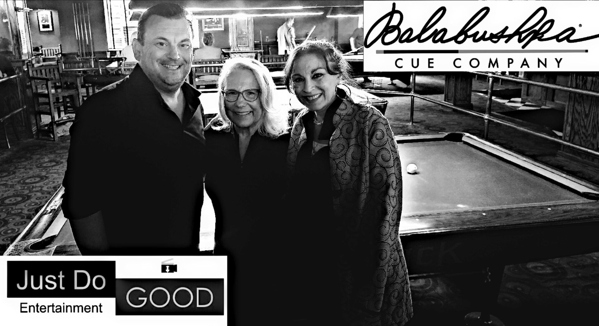 Three people pose near a pool table, with the 