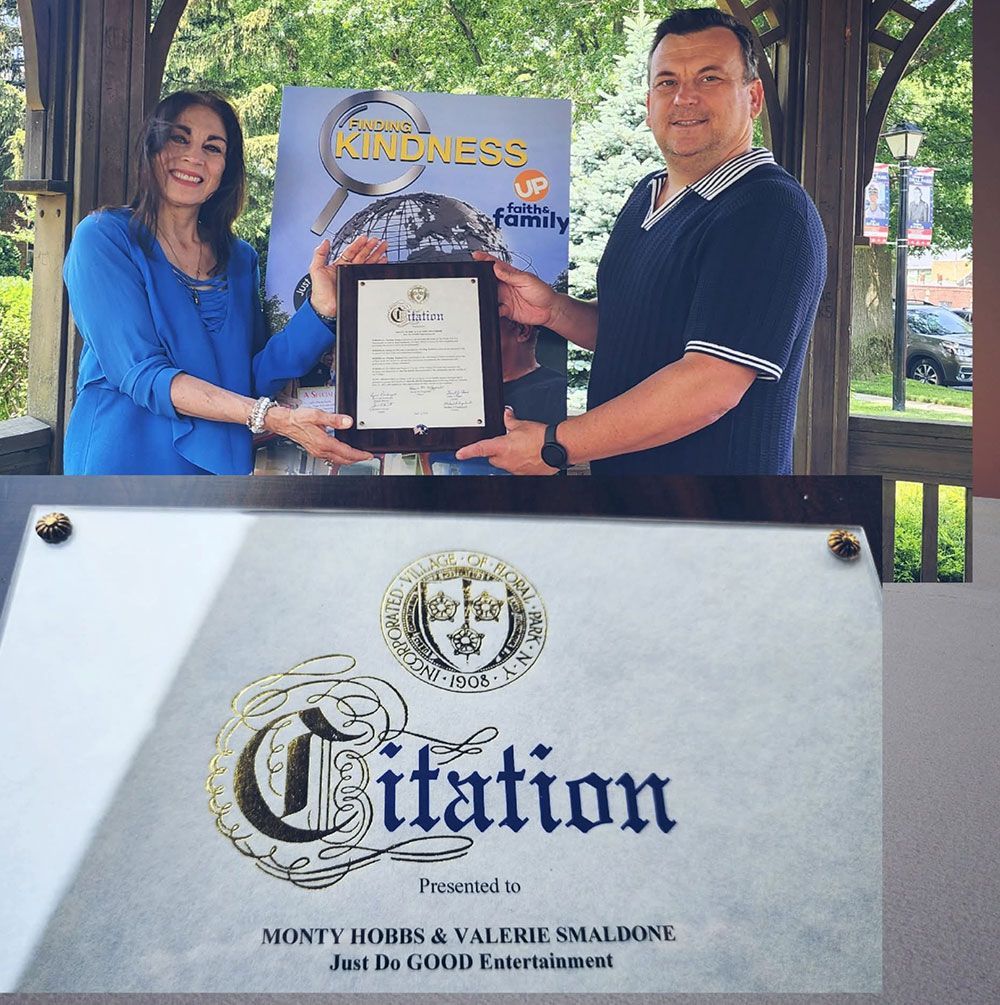 Two people holding a framed citation outdoors, 