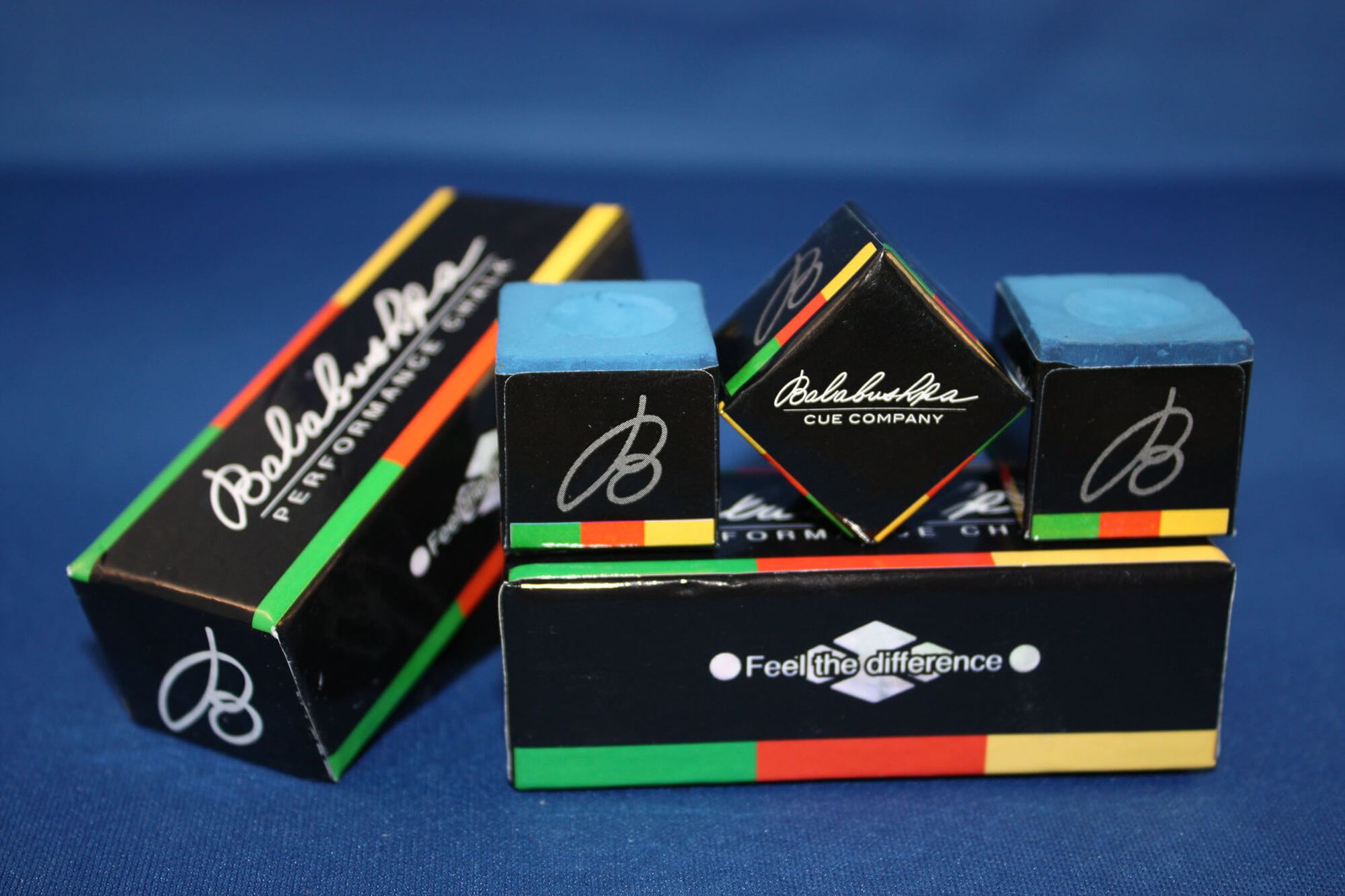 Pool cue chalk boxes and cubes in black with colorful stripes, on a blue surface.