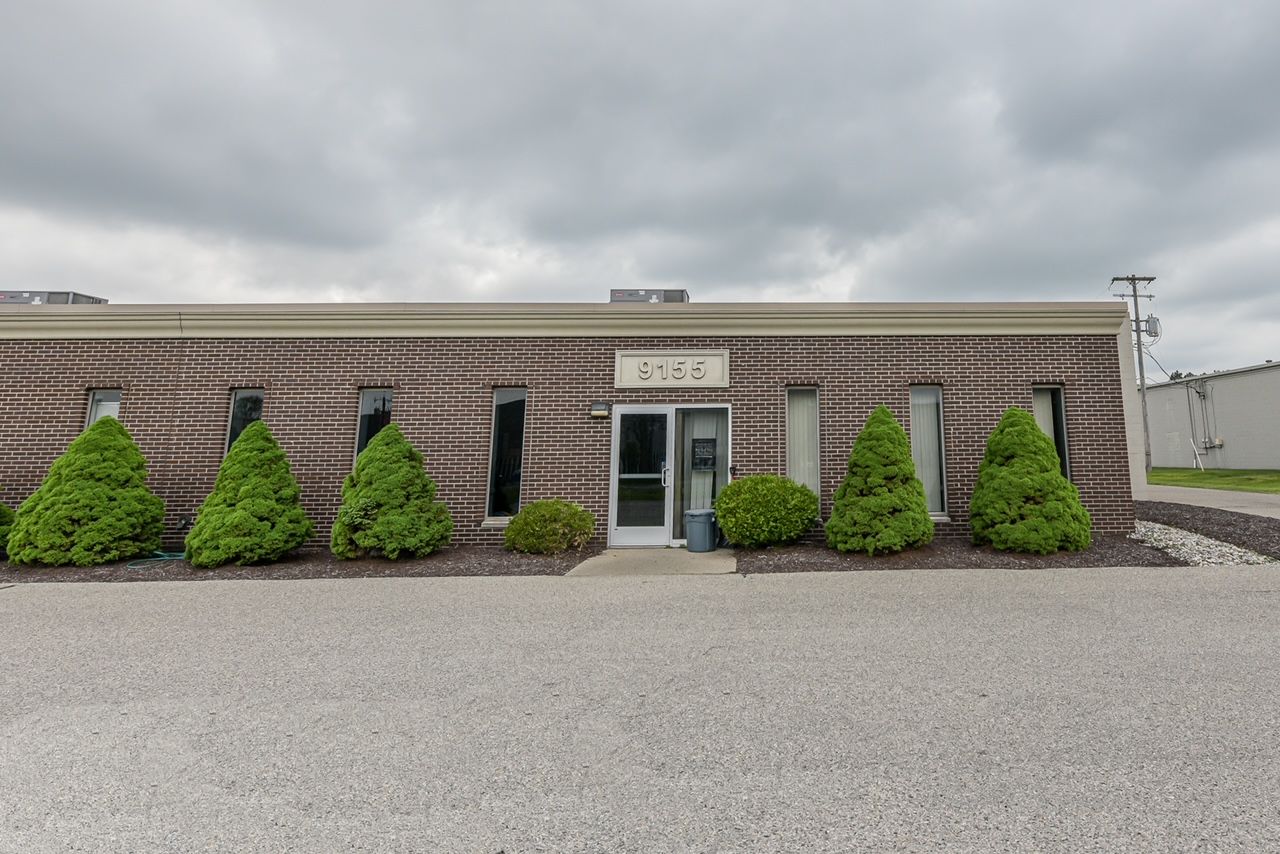 A large brick building with a lot of windows and bushes in front of it.