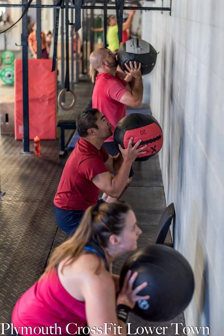 A group of people are doing exercises with medicine balls in a gym in plymouth crossfit lower town