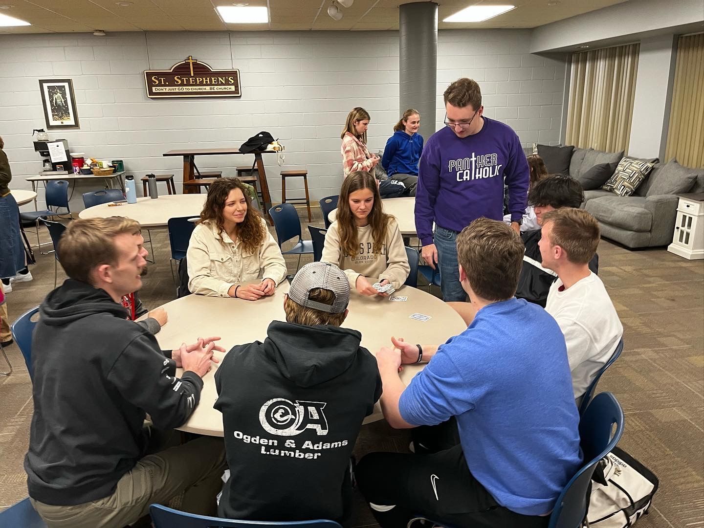 A group of young people are sitting around a table playing cards