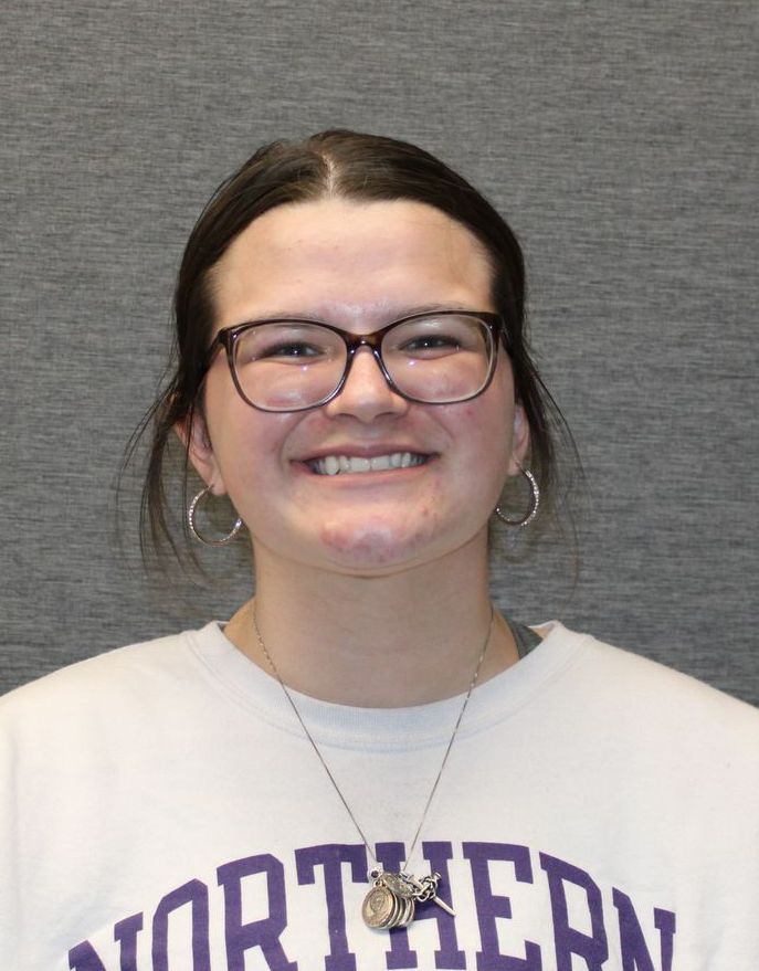 A woman wearing glasses and a northern shirt is smiling for the camera.