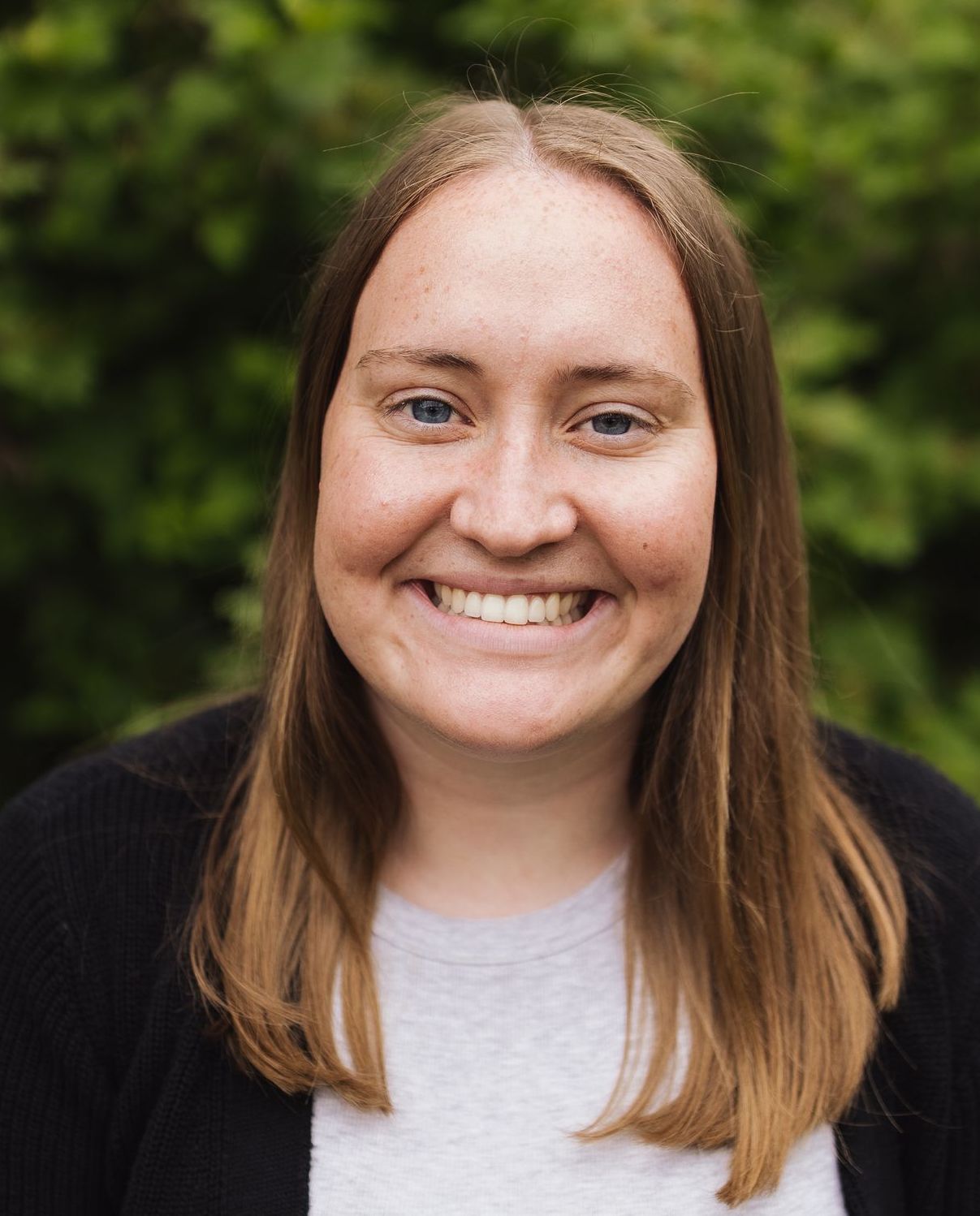 A woman with long brown hair and blue eyes is smiling for the camera.