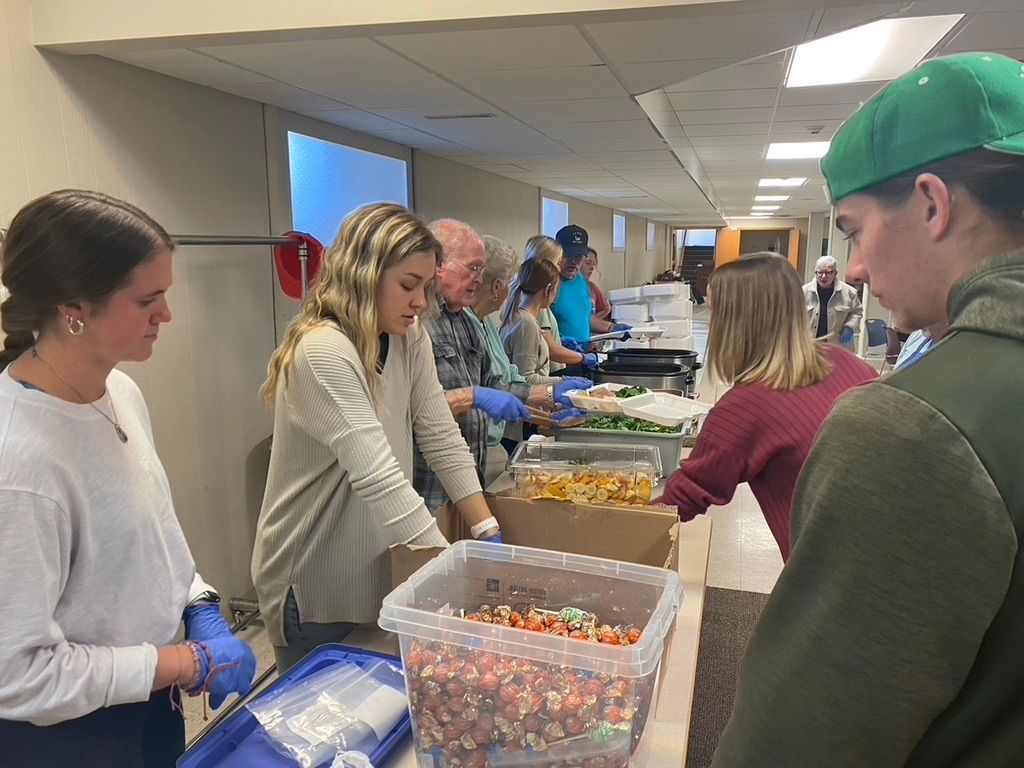 A group of people are standing around a table with boxes of food.