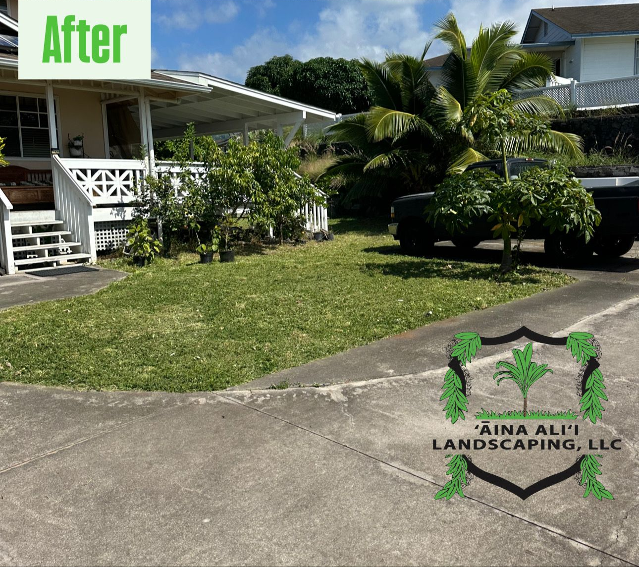 A neatly mowed lawn in front of a white house with a porch and a landscaping company logo in the corner.