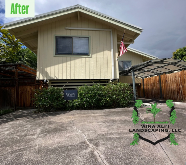 A light yellow house with a groomed hedge, a wooden fence, and a car port, featuring a landscaping company logo.