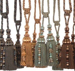 A row of decorative curtain tie-backs featuring braided ropes, tassels, and beaded accents in shades of brown and teal.