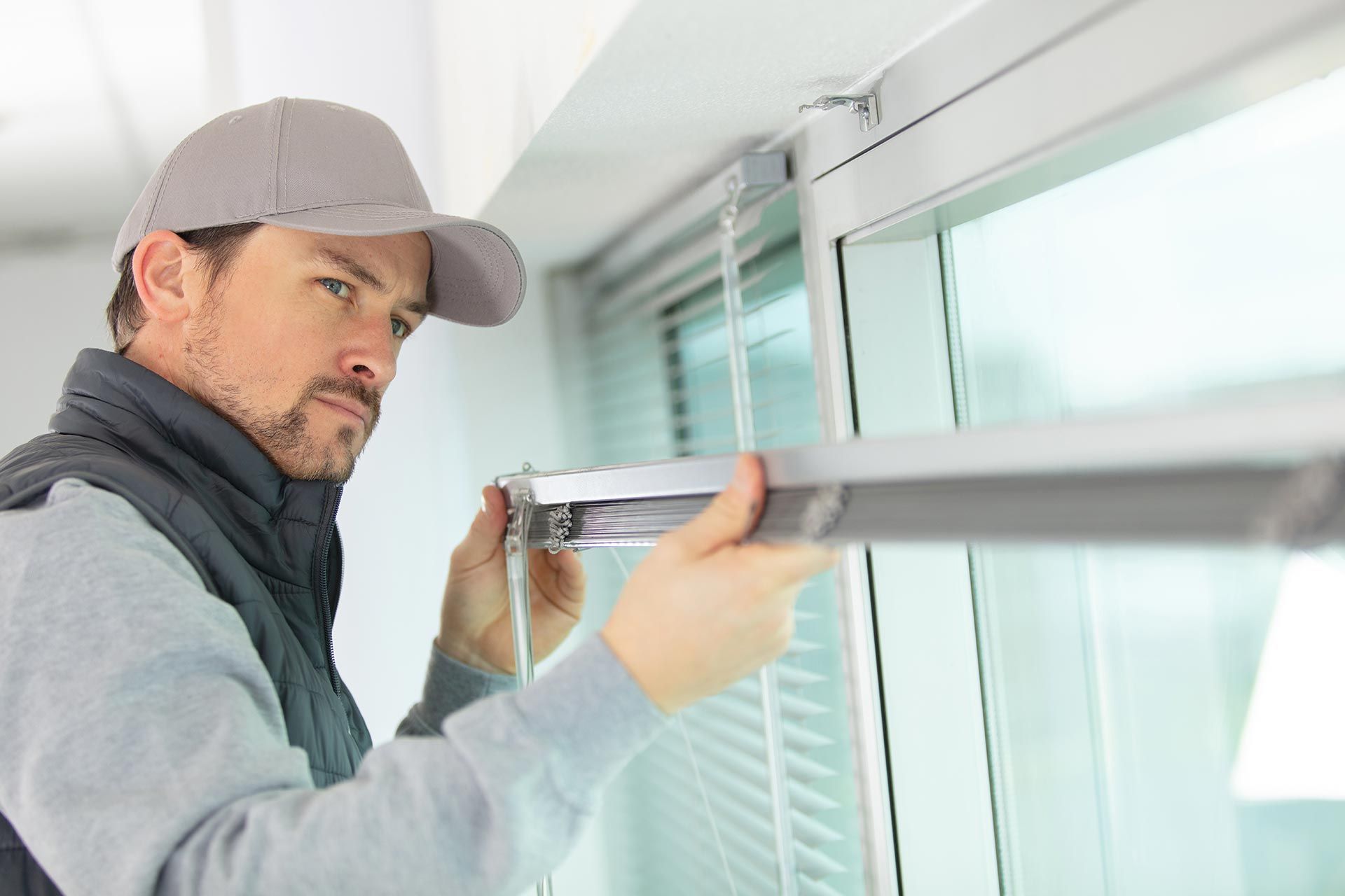 A man is installing a window blind. A man is installing a window blind.