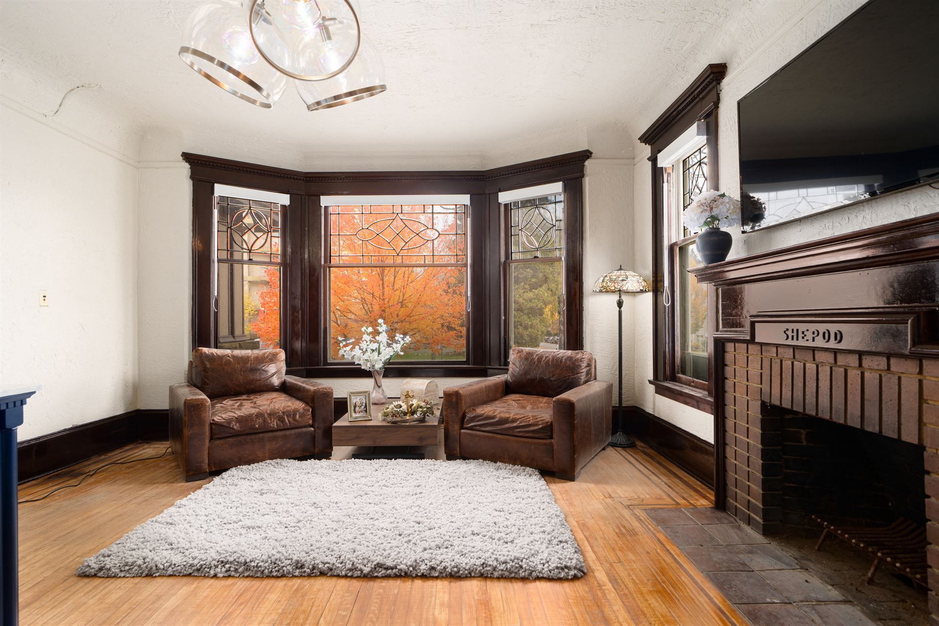 Three rolled towels are sitting on a wooden tray next to a bathtub.