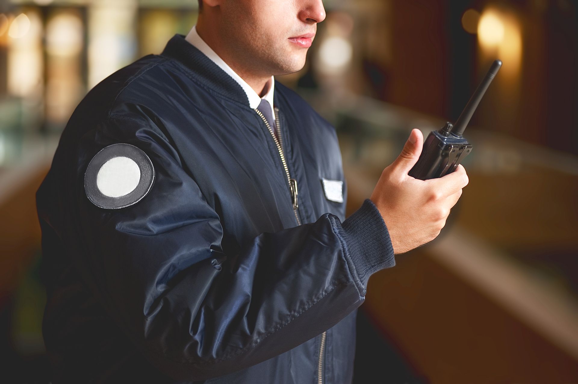 Security guard in blue jacket holds a walkie-talkie