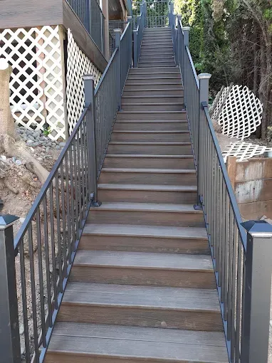 Wooden outdoor staircase with metal railings, leading upwards.