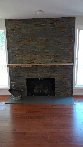 Fireplace with stone facade, wood mantel, and dark gray hearth.