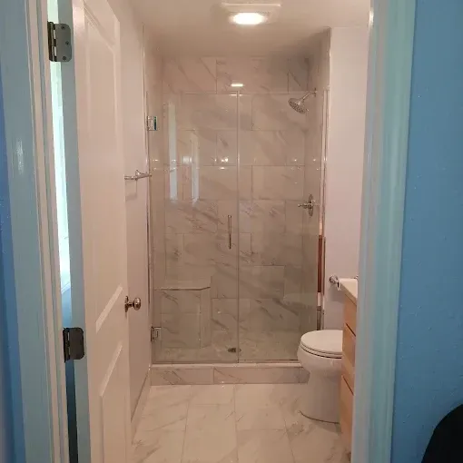 Bathroom view with white marble tile, glass shower, and toilet.