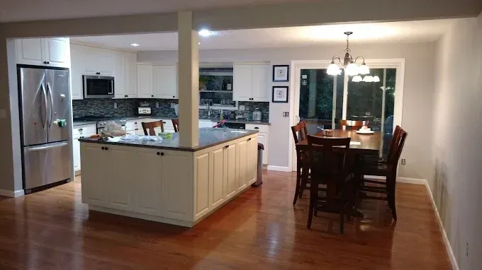 Open-concept kitchen and dining area with cream cabinets, wood floors, and stainless steel appliances.
