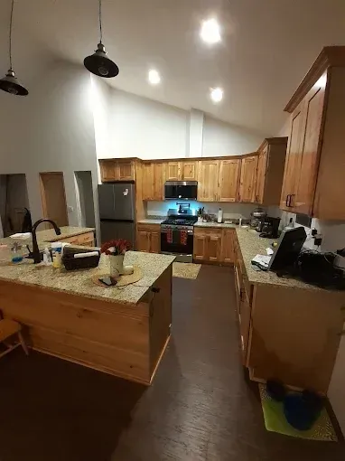 Kitchen with wooden cabinets, island, and stainless steel appliances. Vaulted ceiling with recessed and pendant lights.