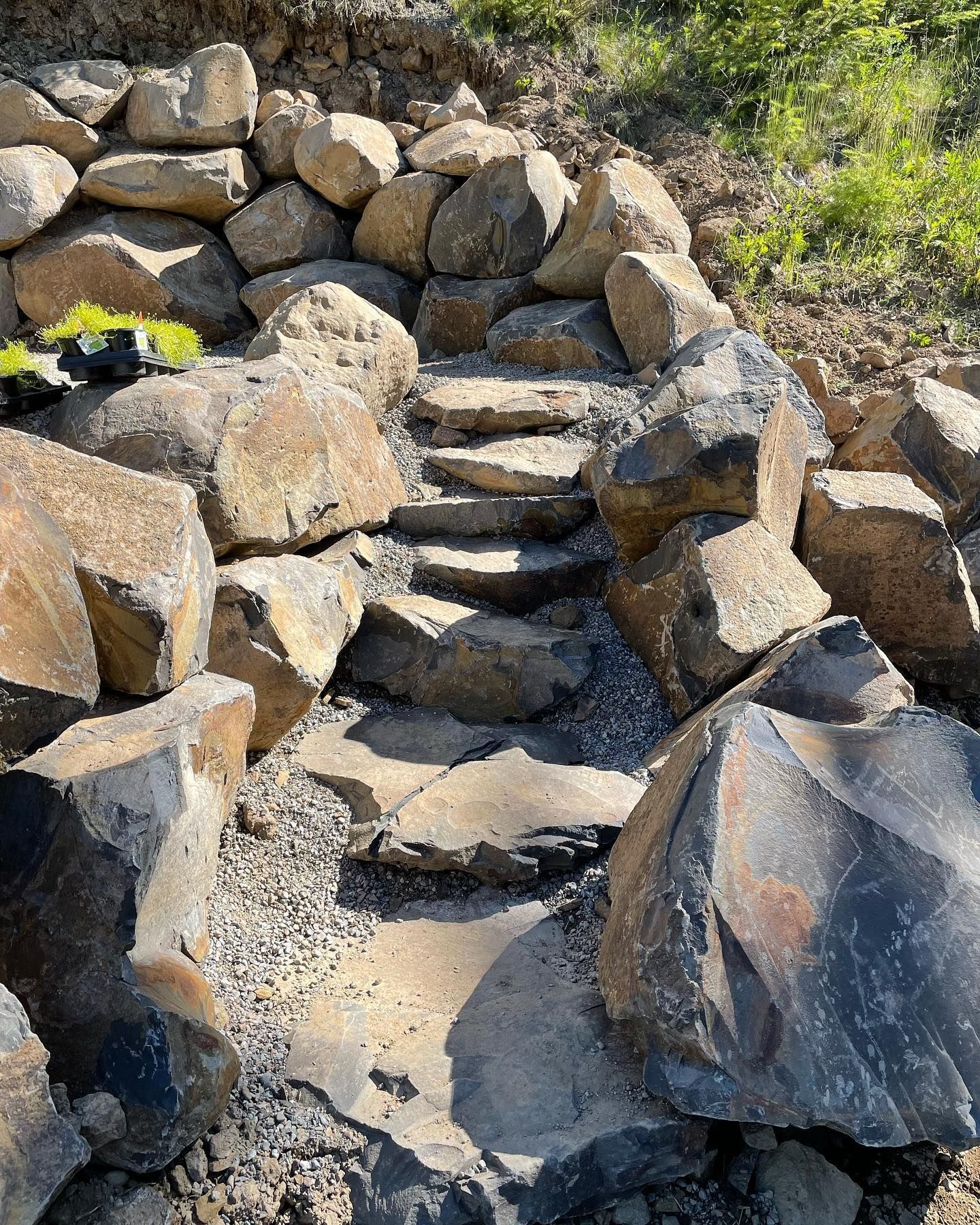 Stone steps and rock retaining walls on a hillside, creating a natural-looking pathway.