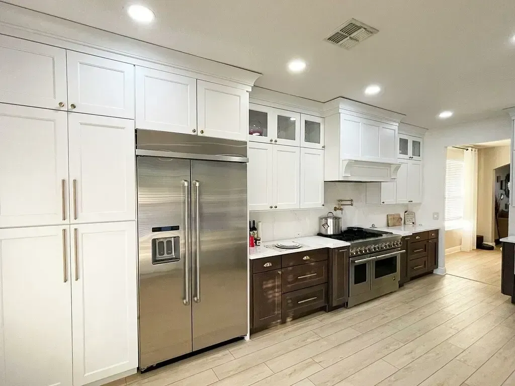 A modern kitchen with white cabinets, stainless steel appliances, and wooden lower cabinets.