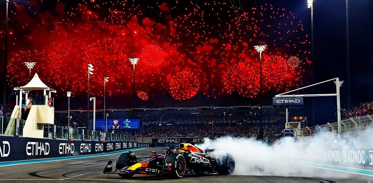 A race car is driving down a track with fireworks in the background.