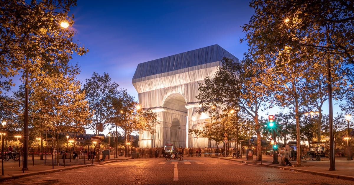 The triumphal arch in paris is surrounded by trees at night.