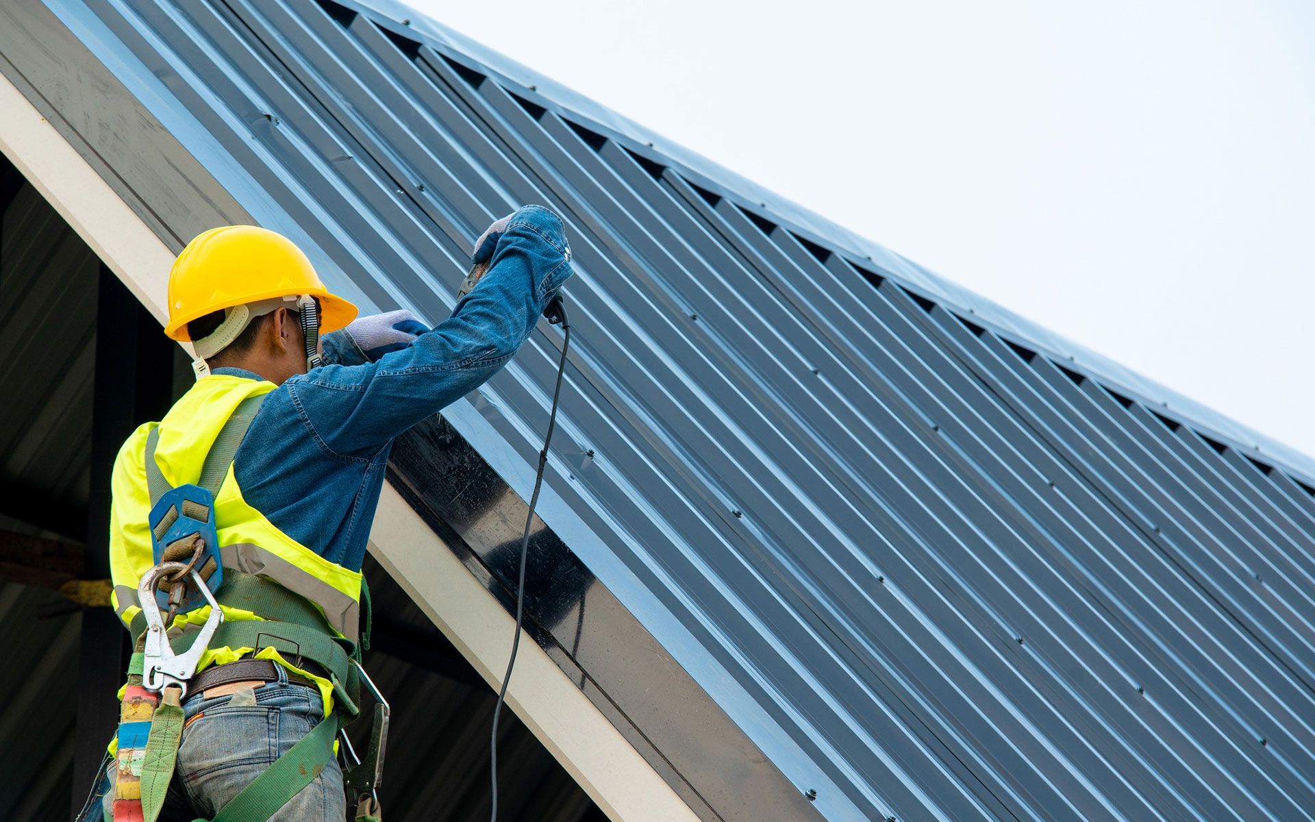 A man is working on a roof with a drill.