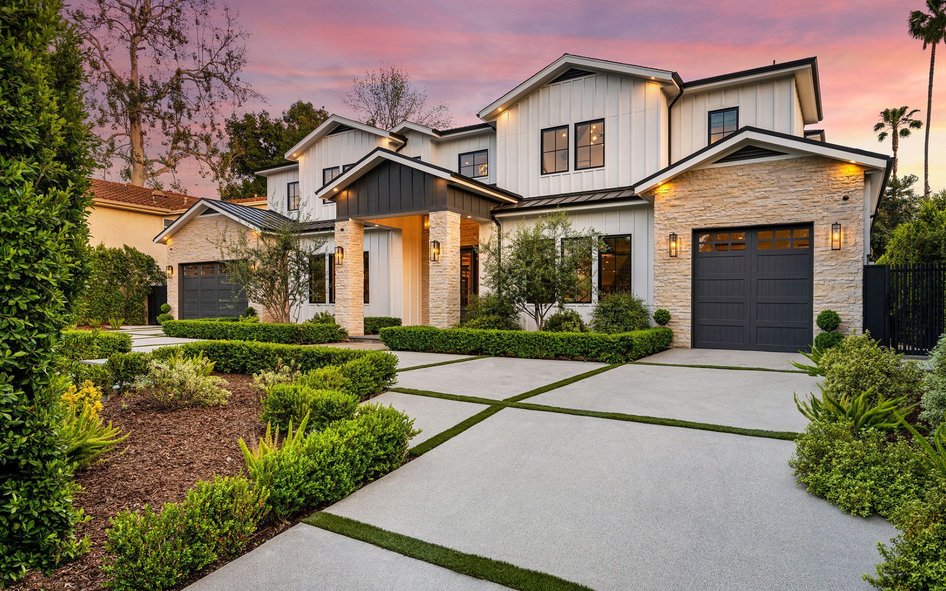 A large white house with a black garage door is for sale.