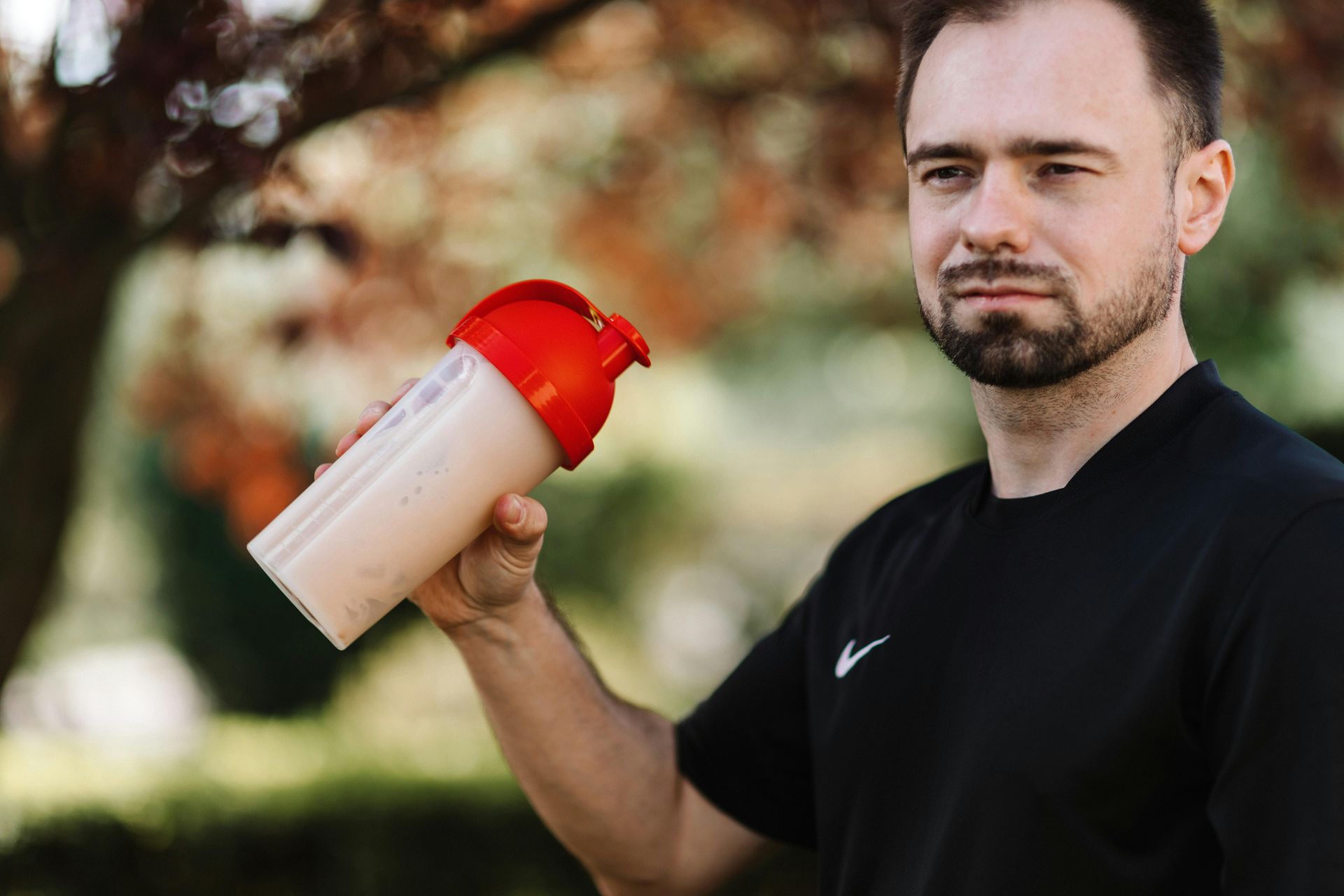 A man is holding a bottle of protein shake in his hand.