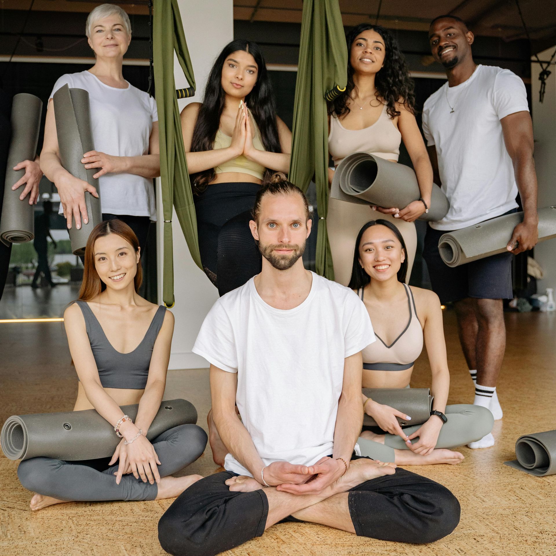 A group of people are sitting on the floor holding yoga mats.