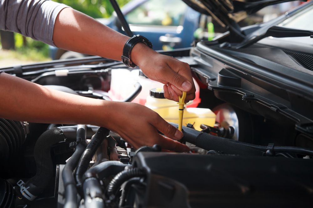 A Person is Checking the Oil Level of a Car With a Dipstick — AVA Automotive Repairs in Oak Flats, NSW