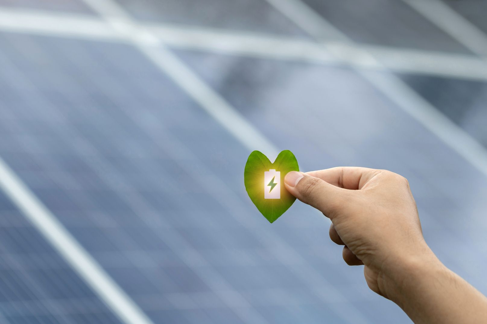 A Person is Holding a Heart Shaped Leaf With a Battery Inside — Robbie McDonald Electrical in Golden Beach, QLD