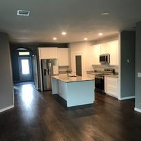 A kitchen with white cabinets , stainless steel appliances , and a large island.
